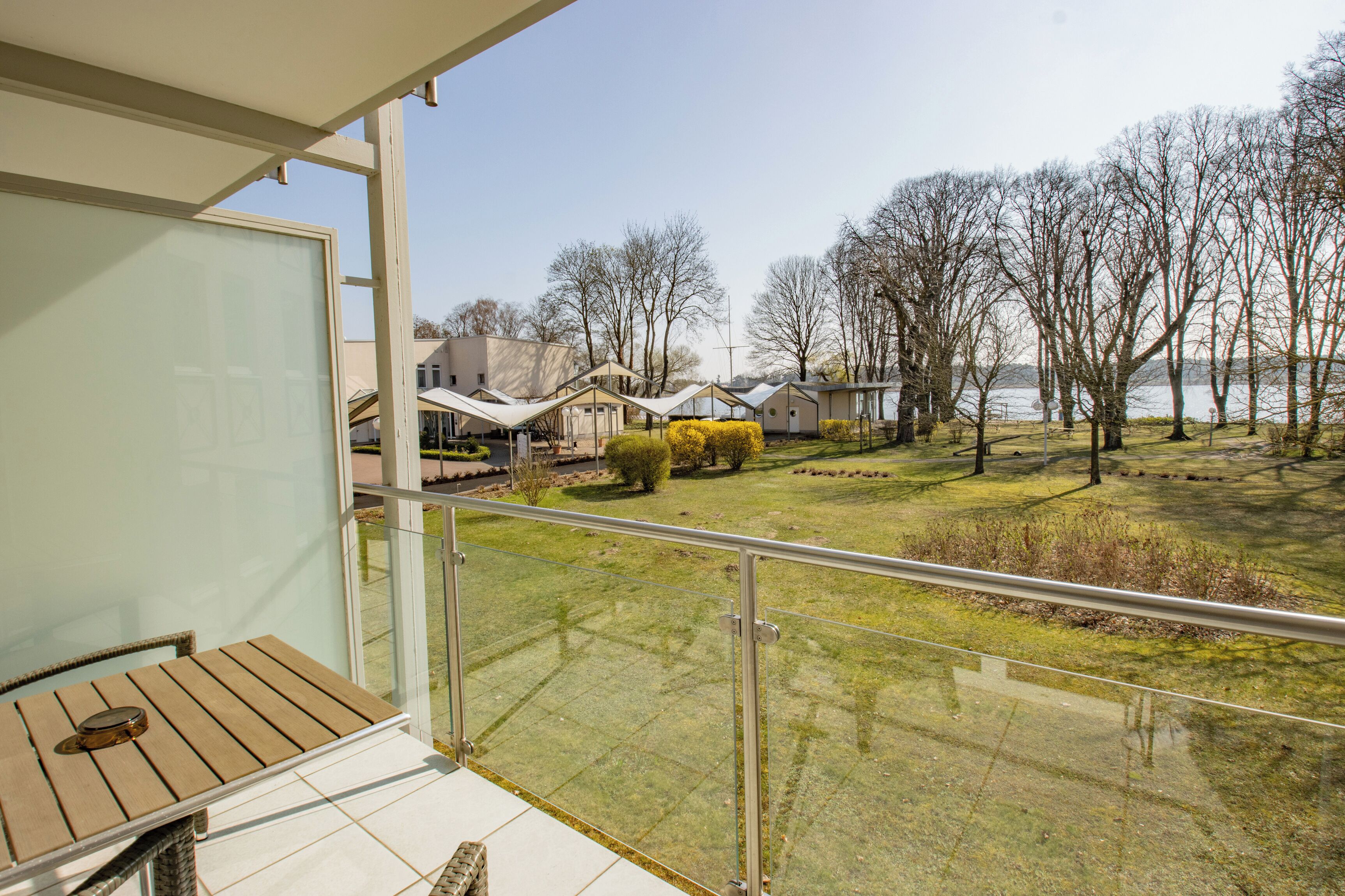 Un balcone con vista su una zona verdeggiante, alberi e case sullo sfondo.