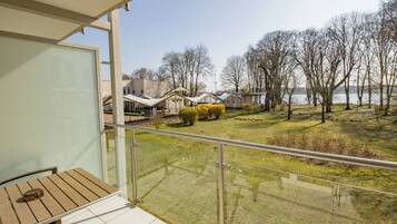Un balcone con vista su una zona verdeggiante, alberi e case sullo sfondo.