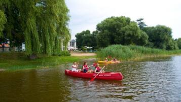 Un grupo de personas en un canoa roja en un río tranquilo, rodeado de vegetación exuberante y árboles.