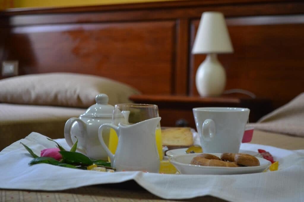 A breakfast setup with a pitcher, cups, and a plate of pastries on a table.