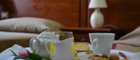 A breakfast setup with a pitcher, cups, and a plate of pastries on a table.