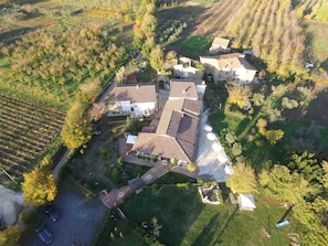An aerial view of a residential area with multiple houses, a paved driveway, and surrounding fields. - Borgo Patierno Agristor Country House (Conca della Campania)