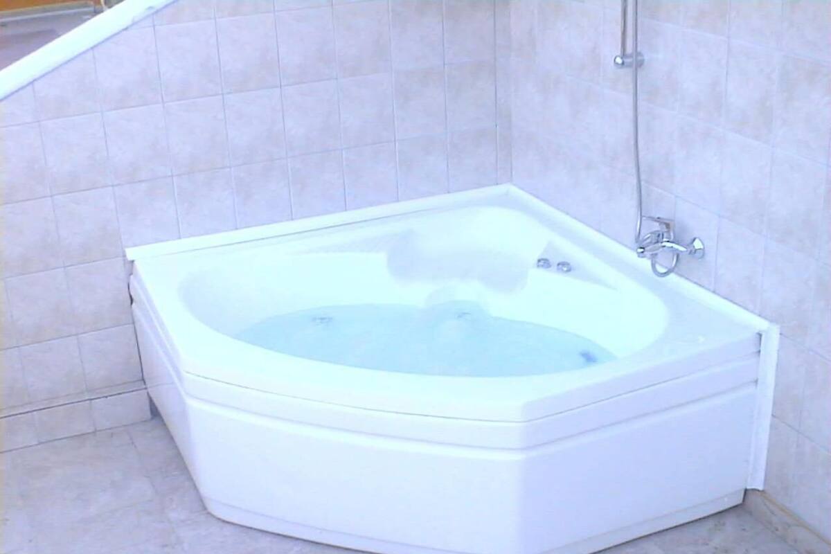 A white hot tub in a bathroom with tiled walls and floor.