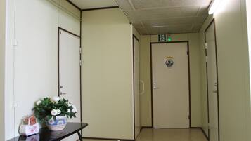 A hallway with a door marked '4', a potted plant, and a small table with a bag and a box.