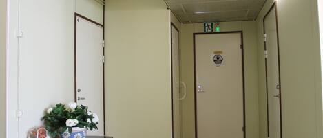 A hallway with a door marked '4', a potted plant, and a small table with a bag and a box.