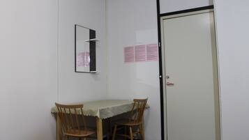 Une petite pièce avec une seule table et deux chaises, une porte et un miroir fixé au mur.