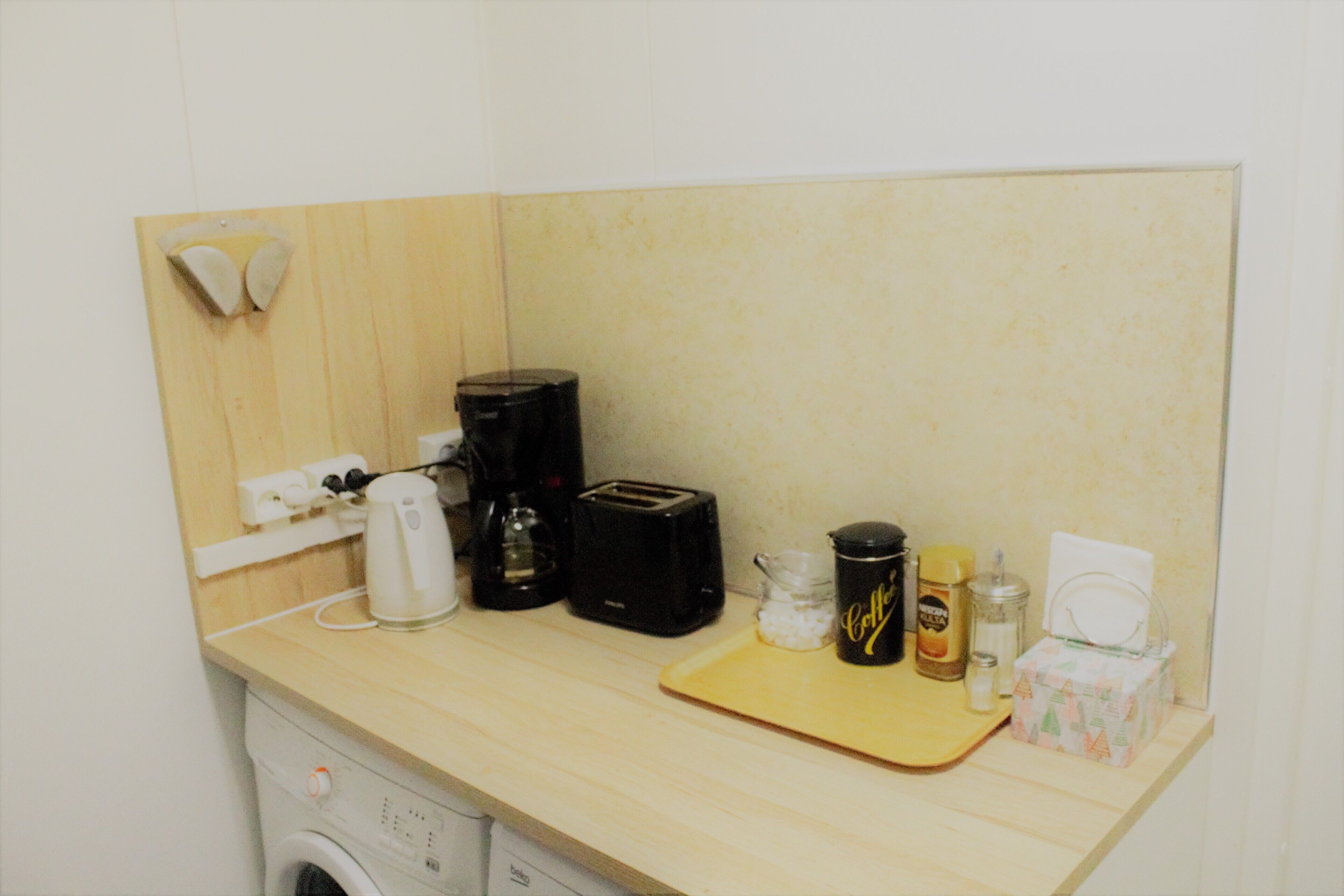 Eine Küchenzeile mit Waschmaschine, Kaffeemaschine, Toaster und Schneidebrett.