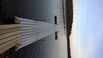 A wooden pier extending into calm water with a forested shoreline in the background.
