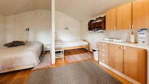 A compact room with a bunk bed, a small kitchenette, and a wooden ceiling.