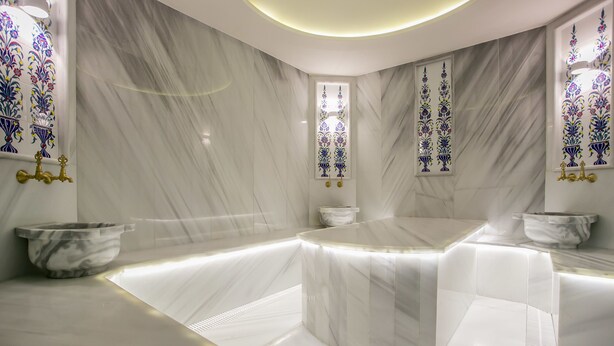 A modern bathroom with marble walls, a central bathtub, and decorative glass panels. - Beyzas Hotel & Suites (Istanbul)