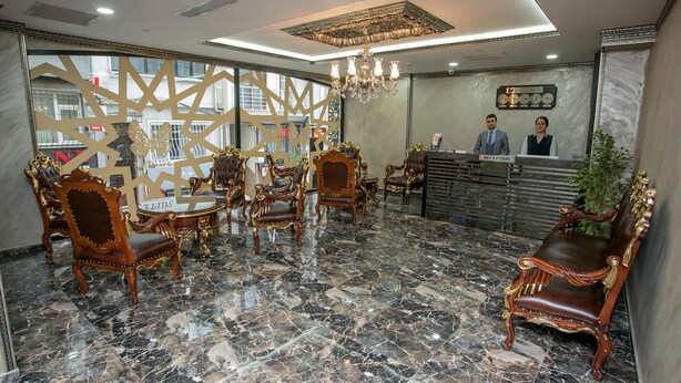 A reception area with marble flooring, ornate wooden chairs, a chandelier, and a reception desk. - Beyzas Hotel & Suites (Istanbul)