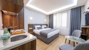 A modern hotel room with a large bed, a desk with a chair, a small table, and a window with curtains. - Beyzas Hotel & Suites (Istanbul)
