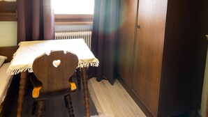 Een kamer met een houten tafel, een stoel, een kledingkast en een raam met gordijnen.