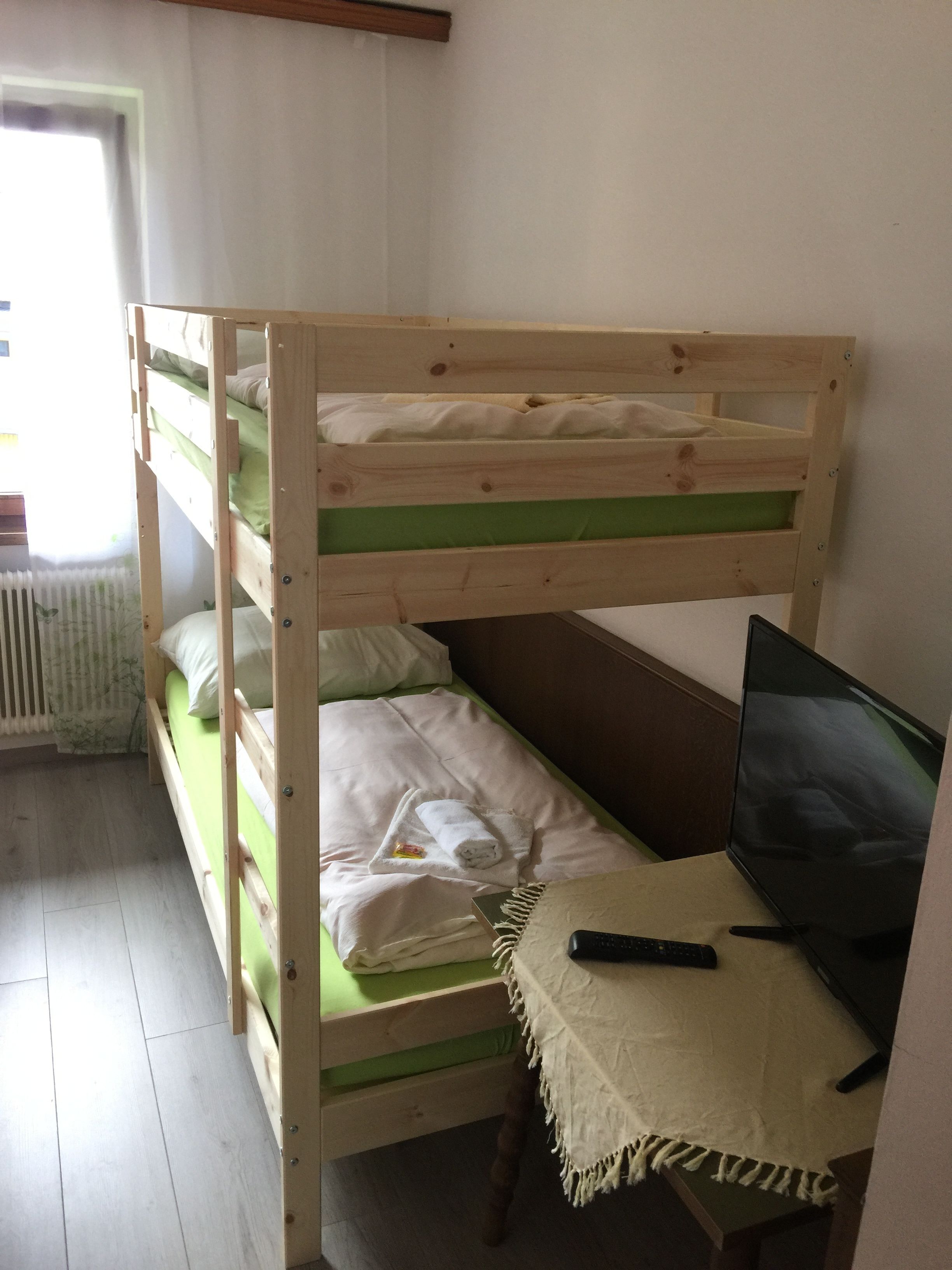 A bunk bed with a desk and a TV.