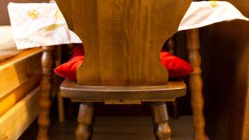 Una silla de madera con un corte en forma de corazón en el respaldo, cojines rojos y suelo de madera.