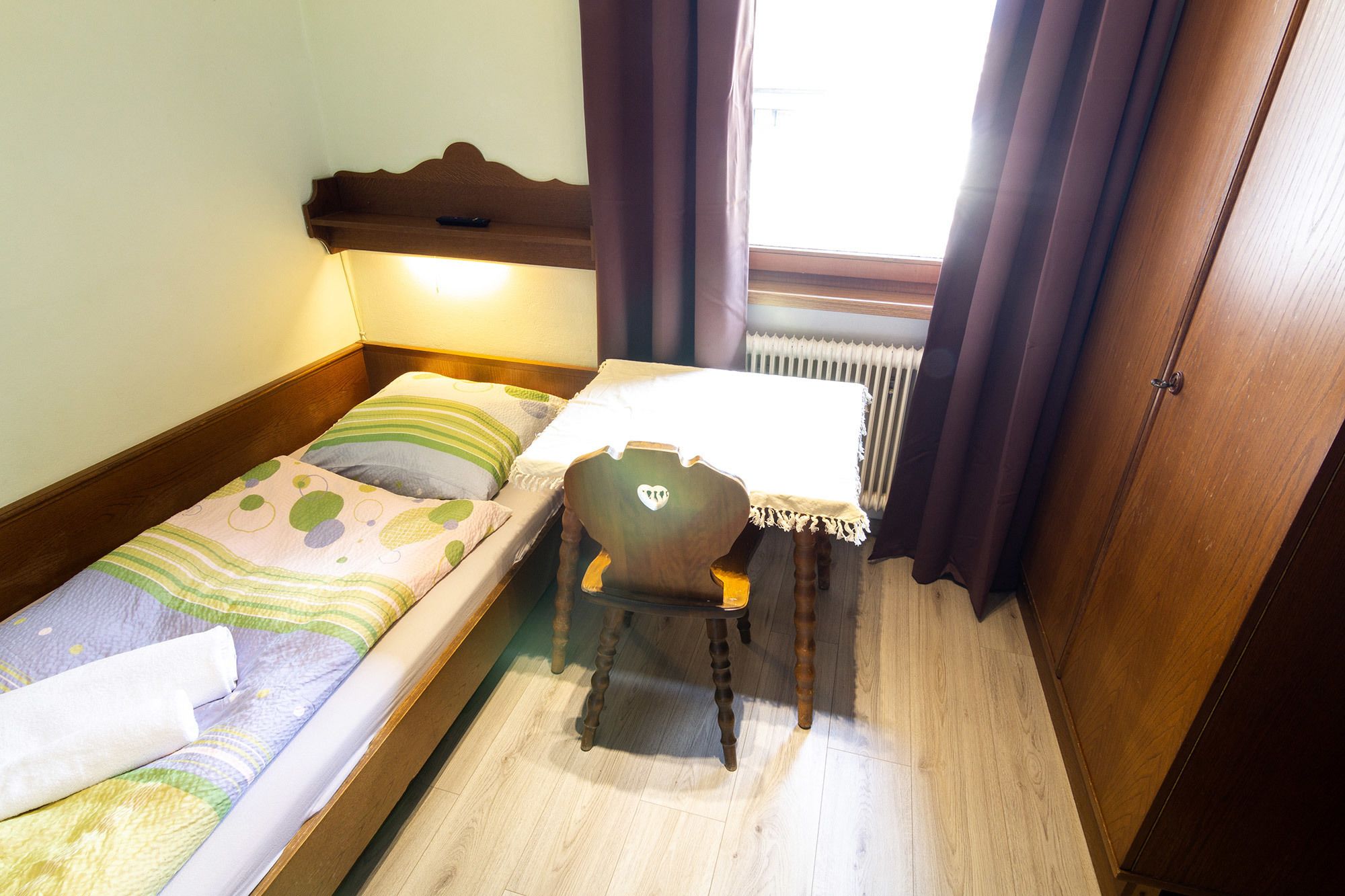 Una habitación pequeña y acogedora con una cama individual, una silla y una mesa.
