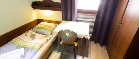 A small, cozy room with a single bed, a chair, and a table.