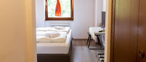 A bedroom with a bed, a desk, and a wardrobe.