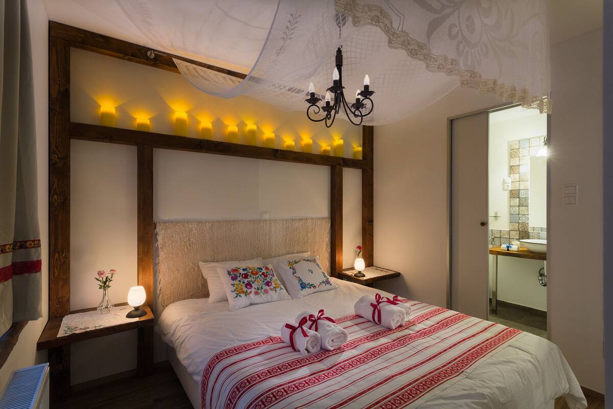 Una habitación de hotel impecable con una cama grande, una araña y una mesita de noche con lámpara.