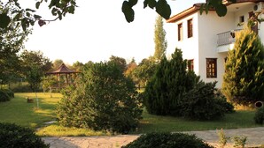 Ein Garten mit einem Pavillon, einem Kiesweg und einem weißen Gebäude mit Balkon.
