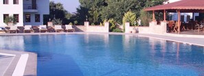 Una piscina al aire libre, sombrillas, sillones reclinables de piscina