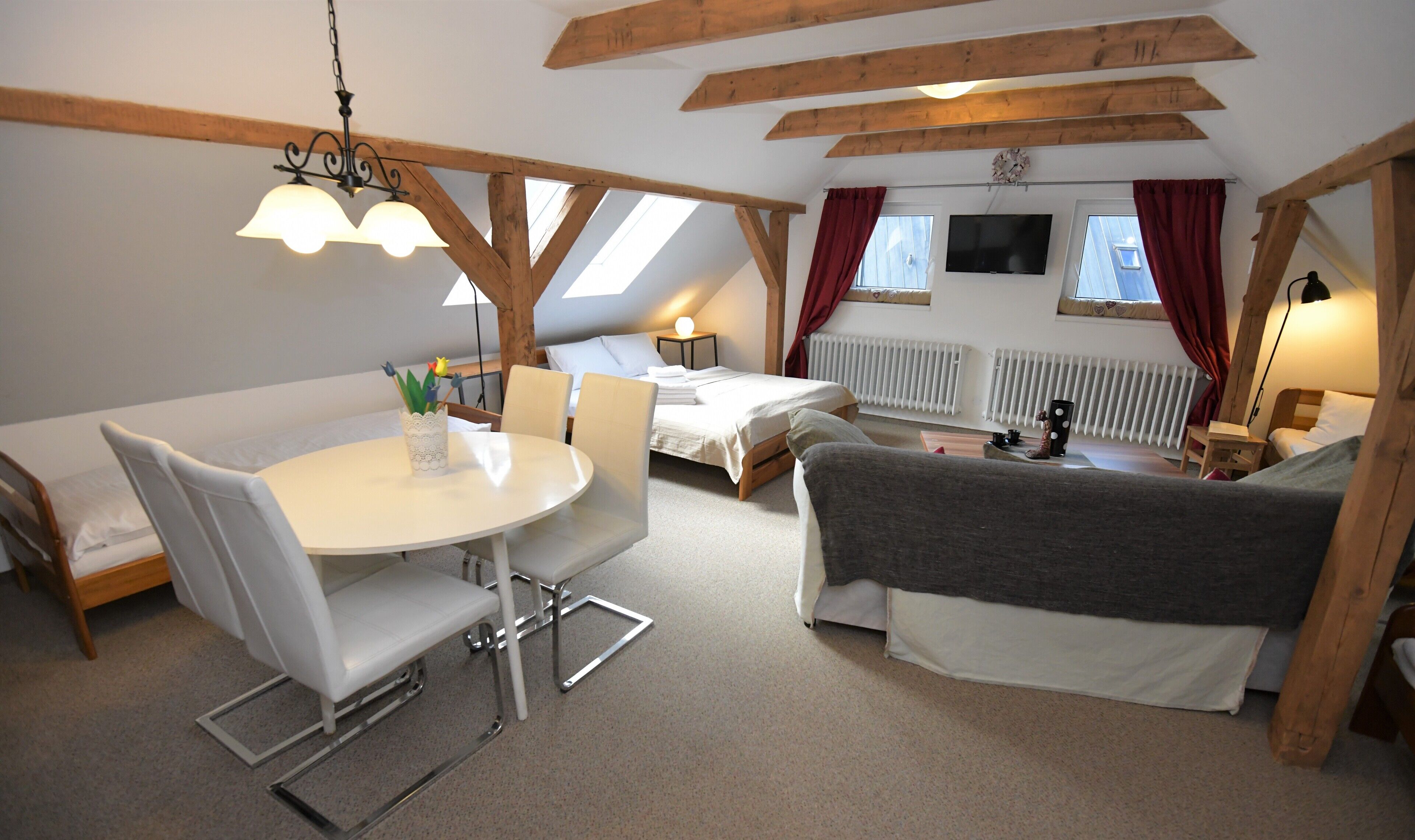 A cozy, well-lit room with a dining table, chairs, a sofa, and a bed.