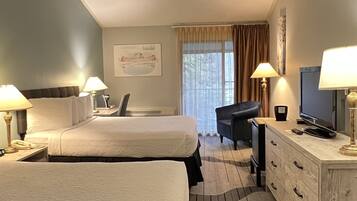 Ein Hotelzimmer mit zwei Betten, einem Schreibtisch mit Fernseher und einem Schminktisch.