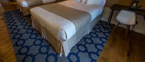 A hotel room with two beds, a desk, and a chair.