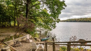 A lakeside deck with Adirondack chairs, a canoe, and a wooden railing. - Interlaken Inn & Resort (Lakeville)