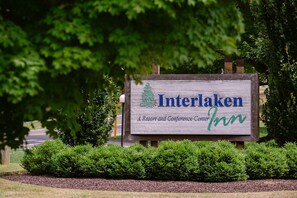 A wooden sign for Interlaken Inn, a resort and conference center, surrounded by greenery.