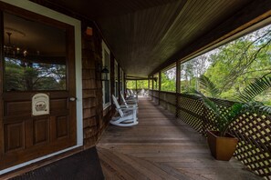 A wooden porch with rocking chairs and a welcome sign.