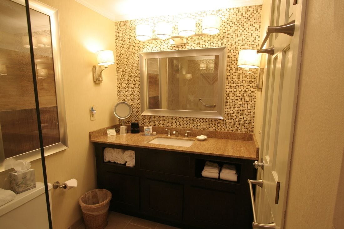 A bathroom with a sink, mirror, and towel rack.