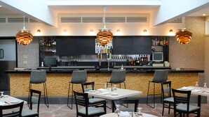 A modern bar area with a counter, bar stools, and a variety of bottles. - Interlaken Inn & Resort (Lakeville)