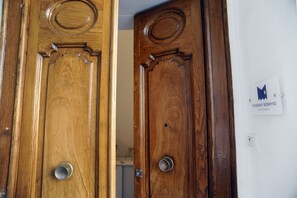 Two wooden doors with metal handles, a white wall with a sign, and a light switch. - Maison Salerno (Salerno)