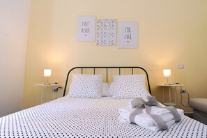 A neatly made bed with a polka dot bedspread, two bedside tables with lamps, and three wall art pieces with text. - Maison Salerno (Salerno)