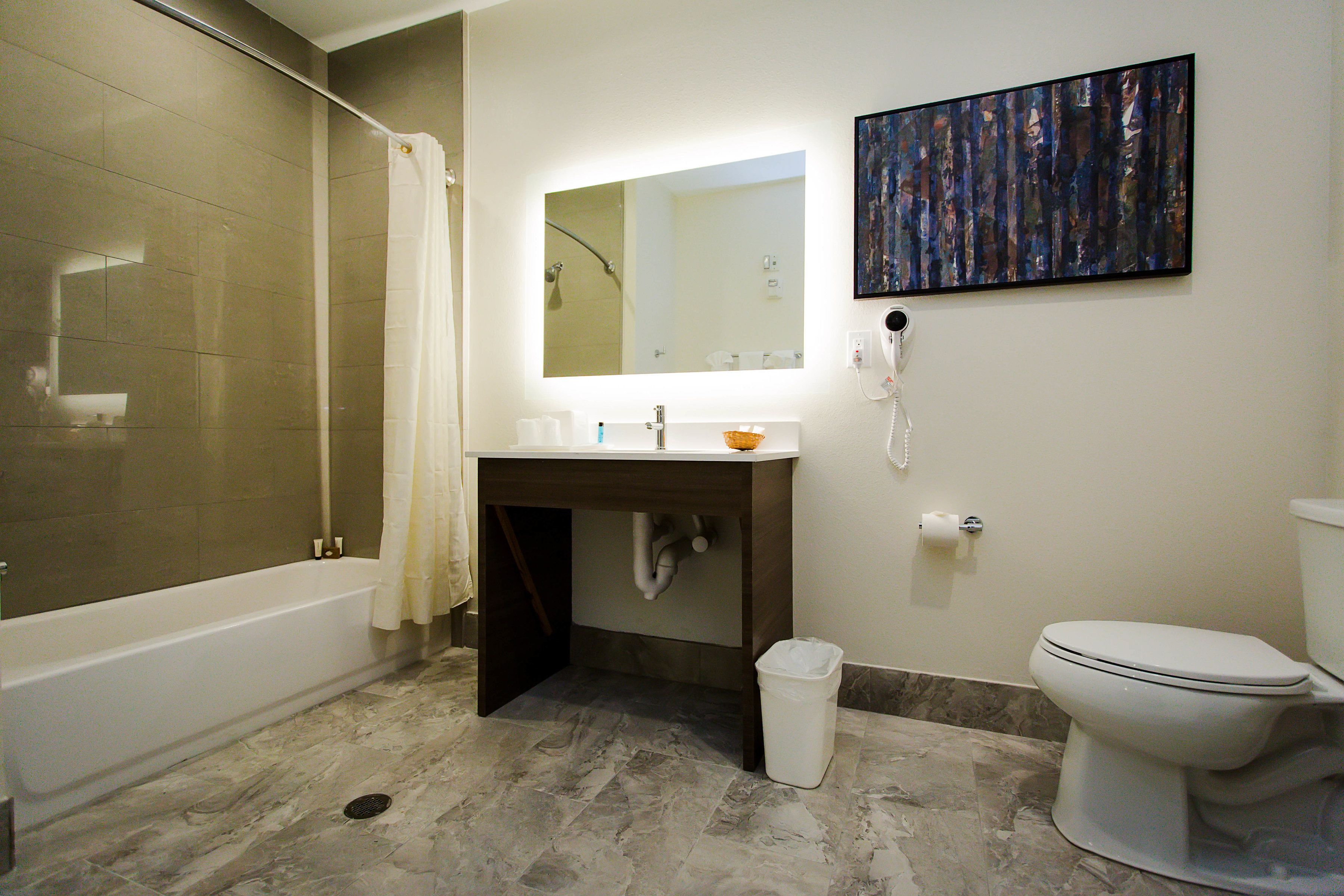 A bathroom with a bathtub, sink, mirror, and toilet.