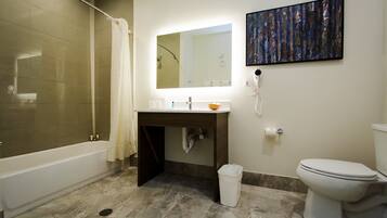 A bathroom with a bathtub, sink, mirror, and toilet.