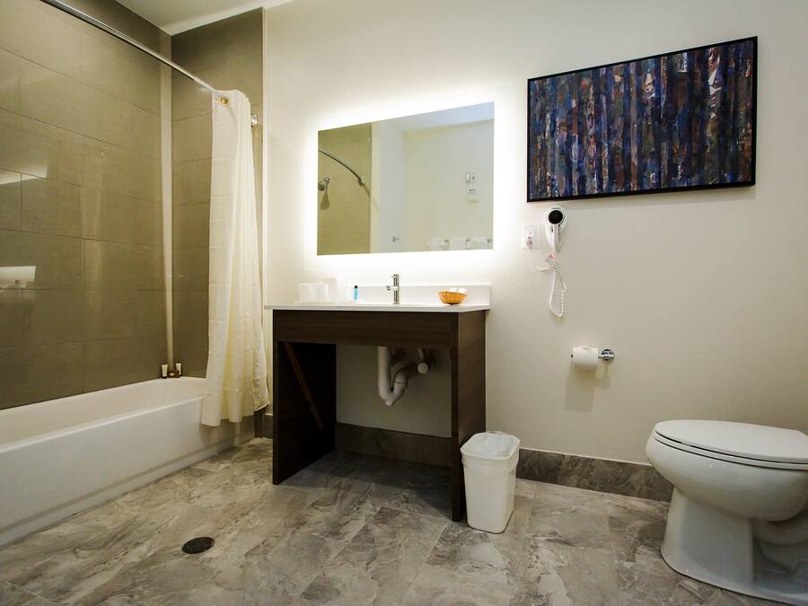 A bathroom with a bathtub, sink, mirror, and toilet.