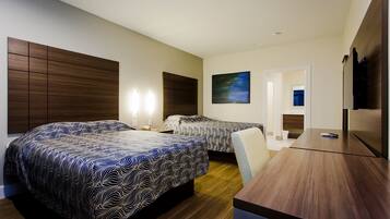 A hotel room with two beds, a desk, and a TV.