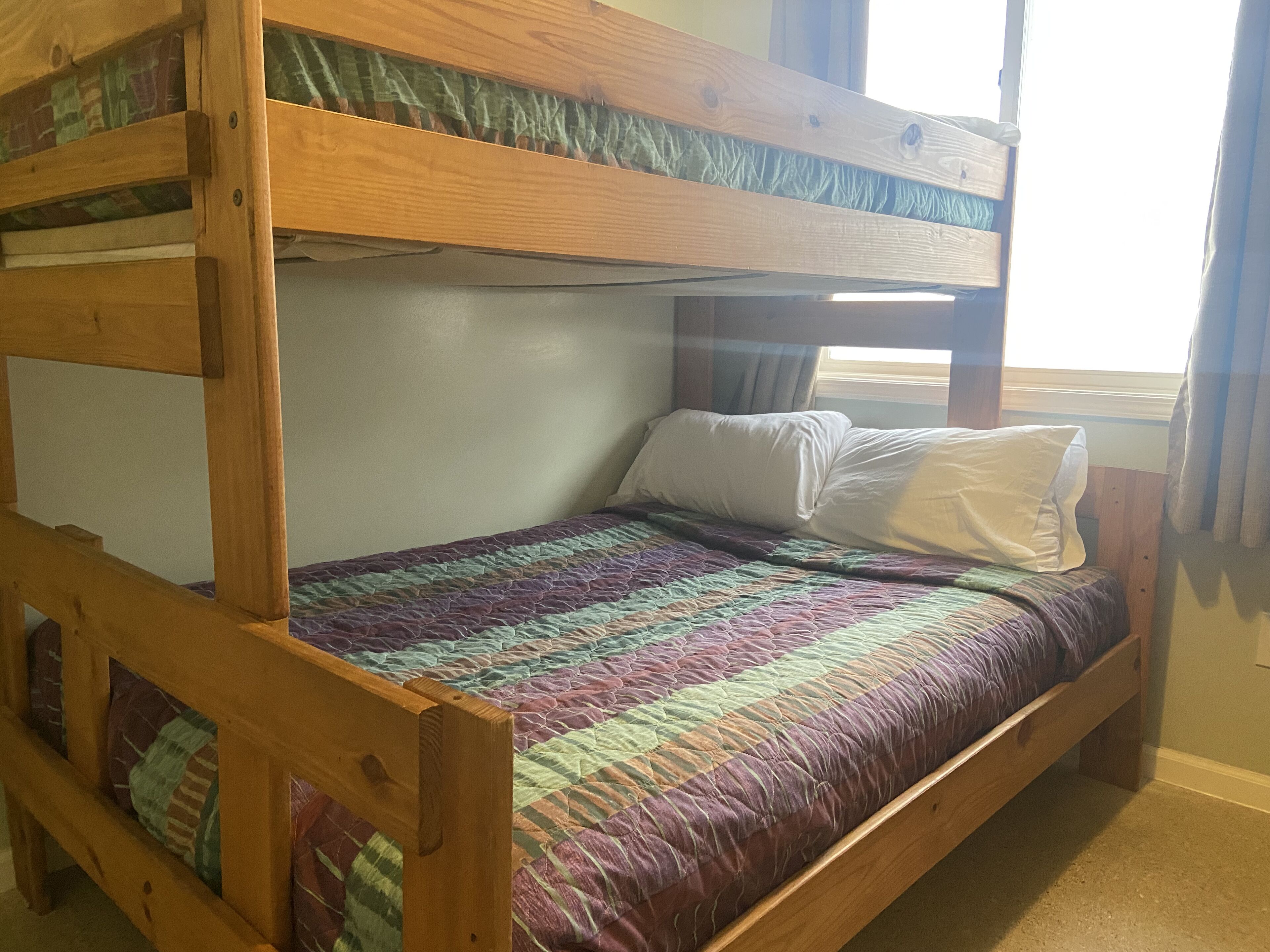 A bunk bed with a quilted bedspread and pillows.