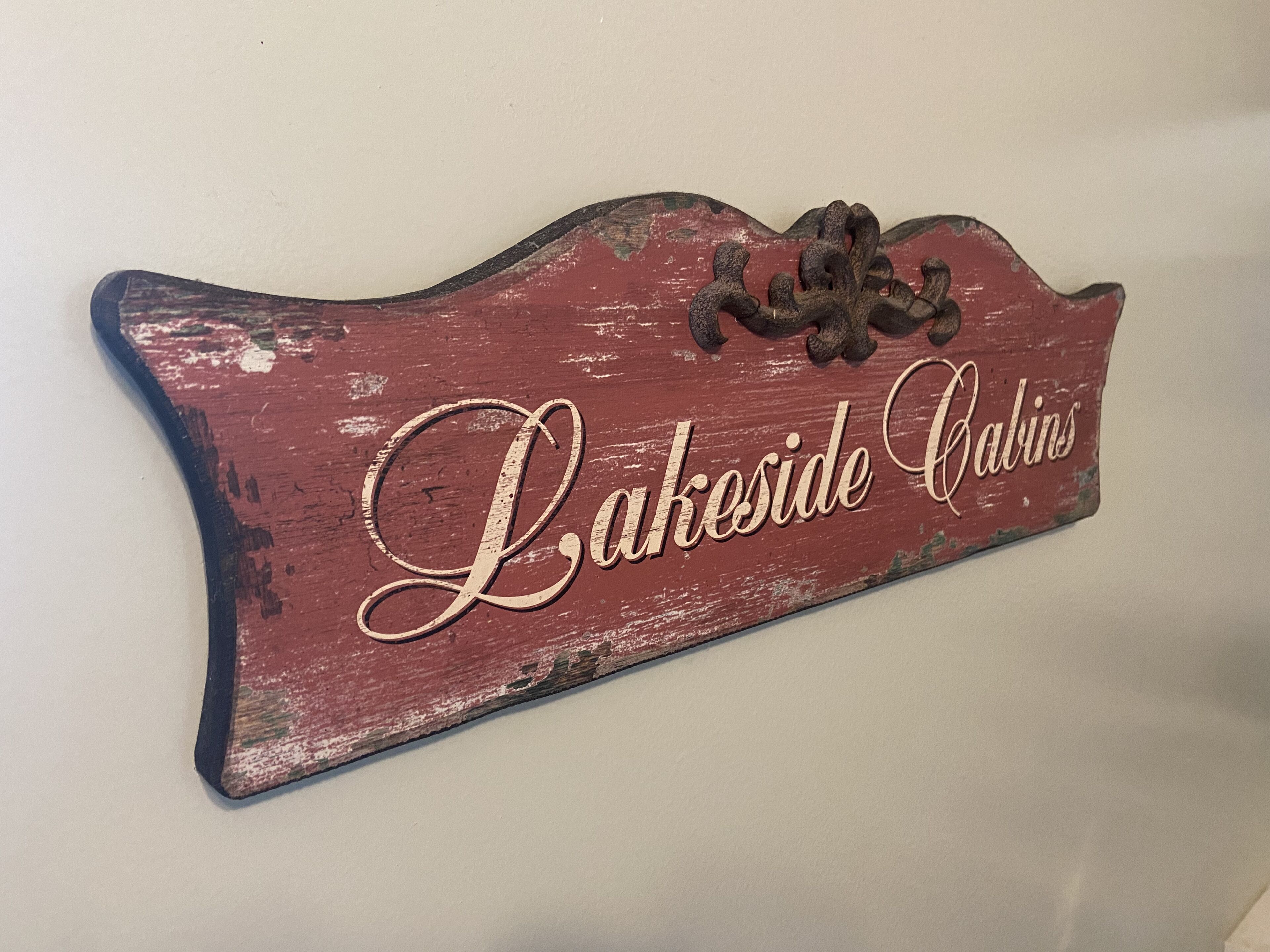 Une enseigne rustique et patinée par les intempéries, portant l’inscription « Lakeside Cabins » en caractères cursifs.