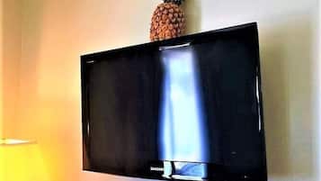 Un televisor de pantalla plana montado en la pared con una piña encima.