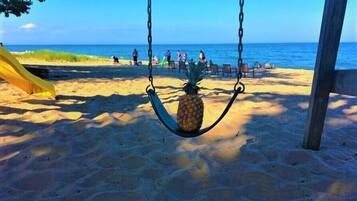 A beach with a swing set holding a pineapple.