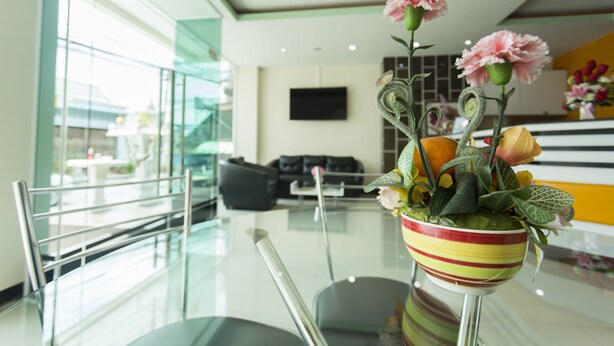 A modern hotel lobby with a glass table, chairs, a sofa, and a decorative plant in a striped bowl. - Kulasab Hotel (Hat Yai)