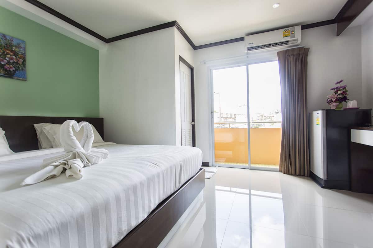 A hotel room with a bed, a desk, a chair, a window, and a door.