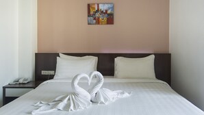 A hotel room with a bed, two pillows, a nightstand with a phone, and a painting on the wall. - Kulasab Hotel (Hat Yai)