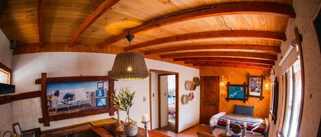 Una cocina rústica con vigas de madera, una mesa de comedor, sillas, un refrigerador y un lavaplatos.
