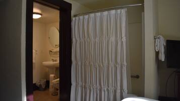 A bathroom with a shower curtain, a sink, and a mirror.