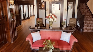A spacious living room with a red sofa, a wooden coffee table, and a chandelier. - The DeLand Hotel (DeLand)