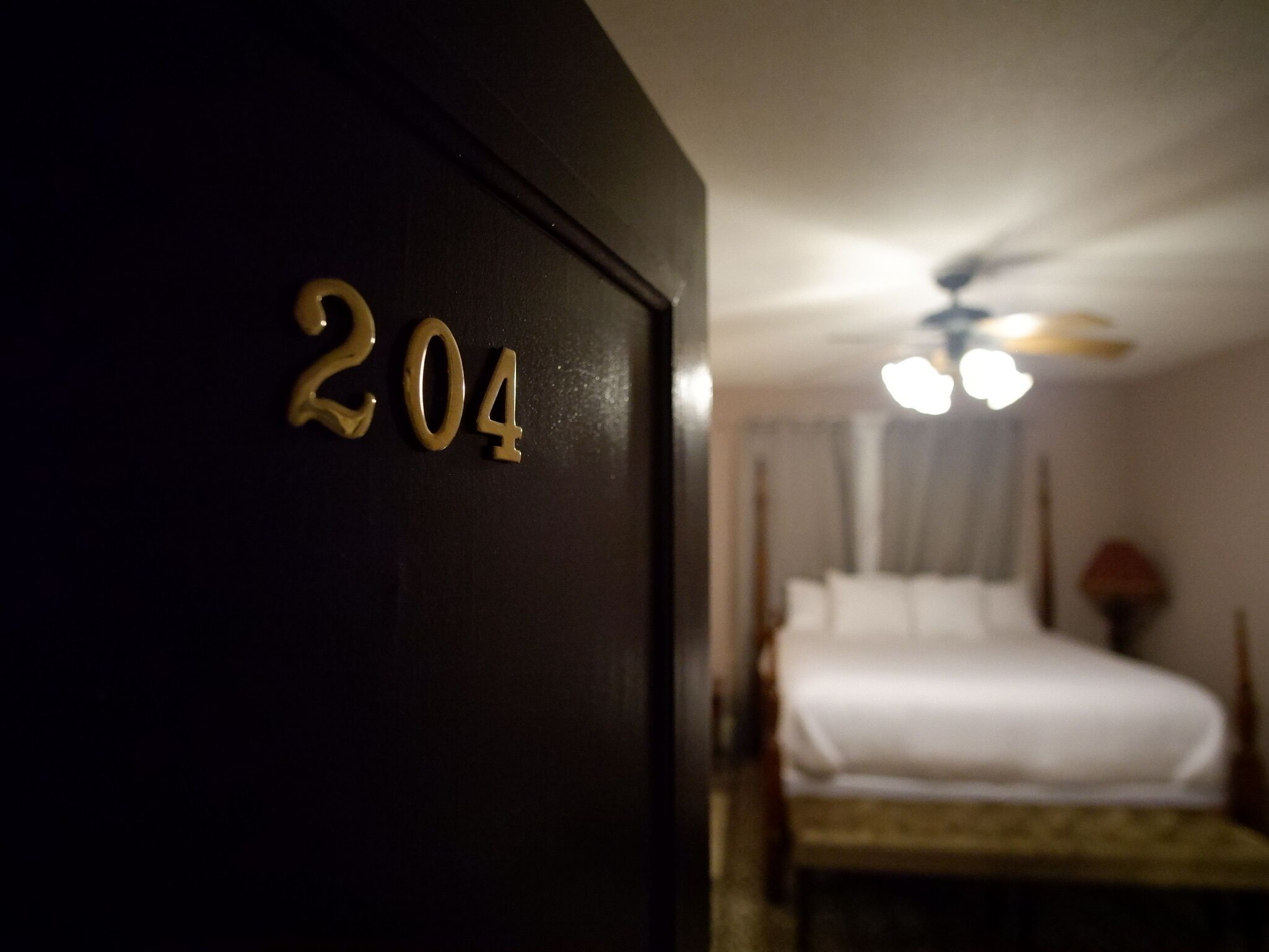 Een hotelkamer met een bed, een plafondventilator en een nachtkastje met een lamp.